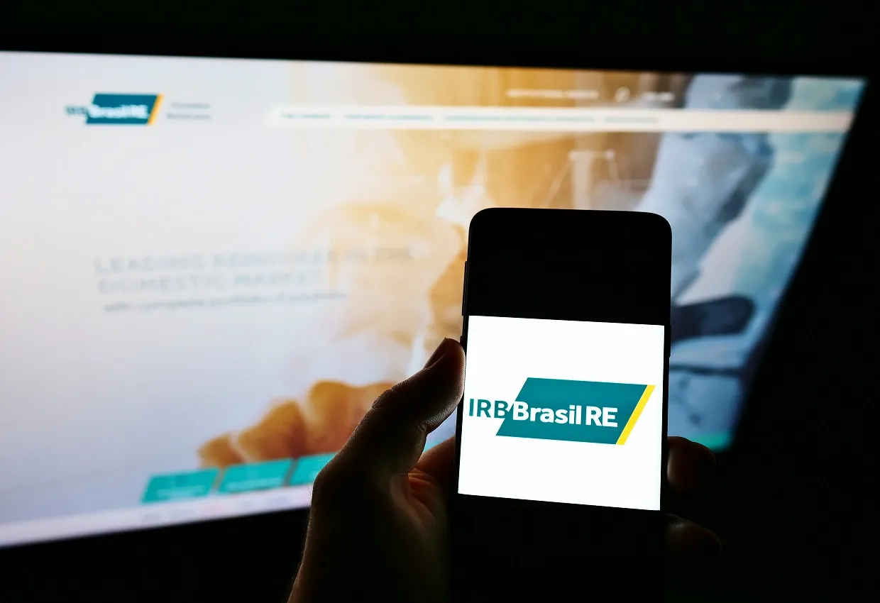 STUTTGART, GERMANY - Feb 10, 2021: Person holding mobile phone with logo of reinsurance company IRB Brasil RE on screen with website.